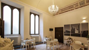 A hotel room with a dining area, a chandelier, and artwork on the wall. - B&B Palazzo del Magnifico (Siena)
