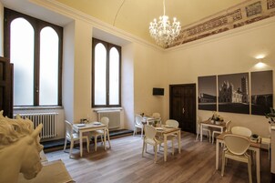 Camera d'albergo con zona pranzo, un lampadario e opere d'arte alle pareti.