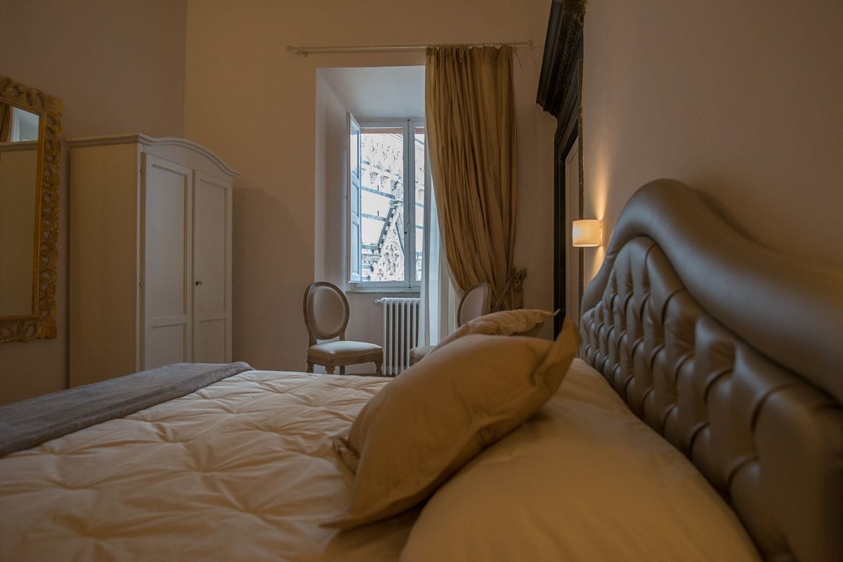 Une chambre avec un grand lit, une armoire, une chaise et une fenêtre avec des rideaux.