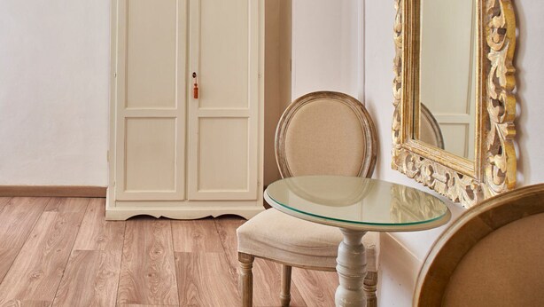 A room with a white wardrobe, a glass-top table, a chair, and a large ornate mirror. - B&B Palazzo del Magnifico (Siena)