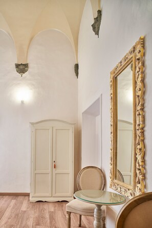 Una habitación con un armario blanco, una mesa con cubierta de vidrio, una silla y un espejo grande y decorado.