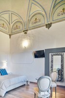 Una camera da letto con un letto, due sedie, una TV e un grande specchio.