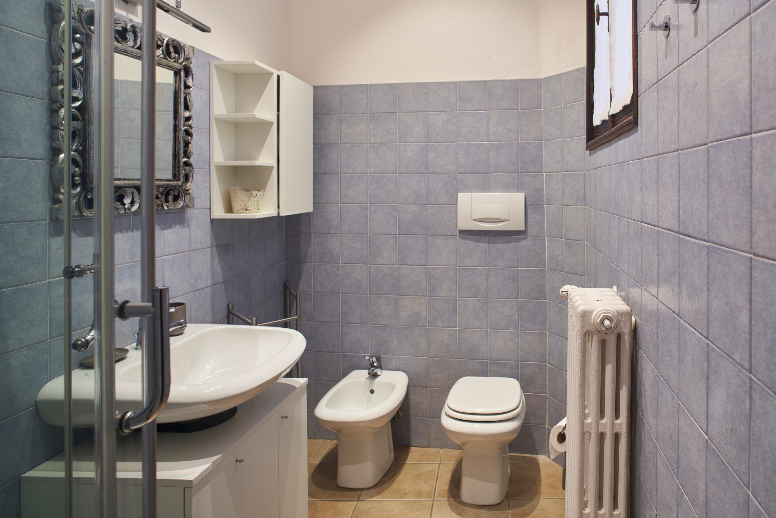 A bathroom with a sink, bidet, toilet, and a mirror.