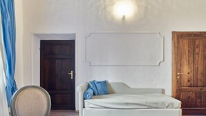 A bedroom with a bed, a chair, a wooden door, and a wall-mounted light fixture. - B&B Palazzo del Magnifico (Siena)
