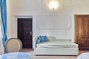 Una camera da letto con un letto, una sedia, una porta in legno e un lampadario a parete.