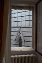 Una finestra che mostra una vista dell'esterno di un edificio, con una facciata decorata e un arco gotico.
