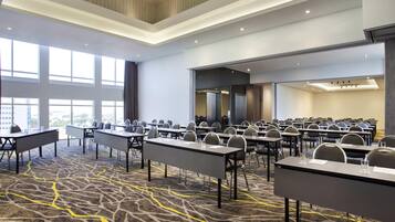 A conference room with multiple tables and chairs, large windows, and a patterned carpet.