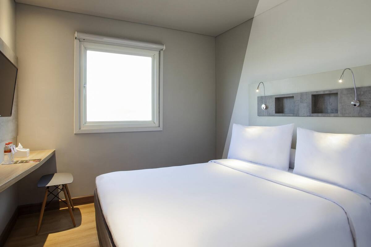 Un dormitorio moderno con una cama grande, un escritorio y un ventanal.