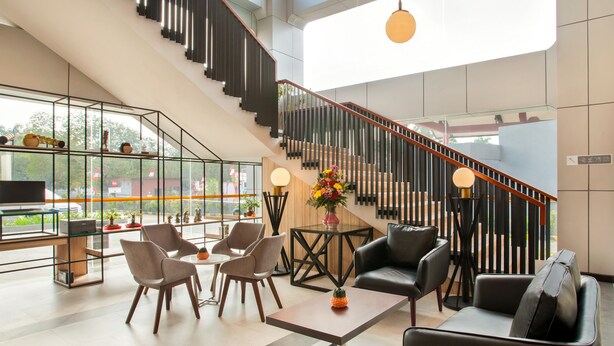 Un vestíbulo amplio con una escalera moderna, asientos cómodos y un ventanal con vistas al exterior.