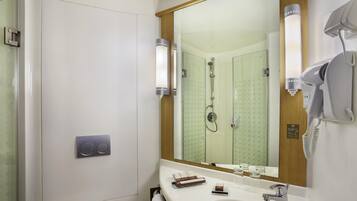 Un baño con un espejo grande, un secador de pelo, un lavabo y una ducha.