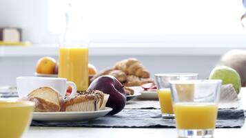 A breakfast setting with a croissant, a muffin, a glass of orange juice, and a plate of fruit.