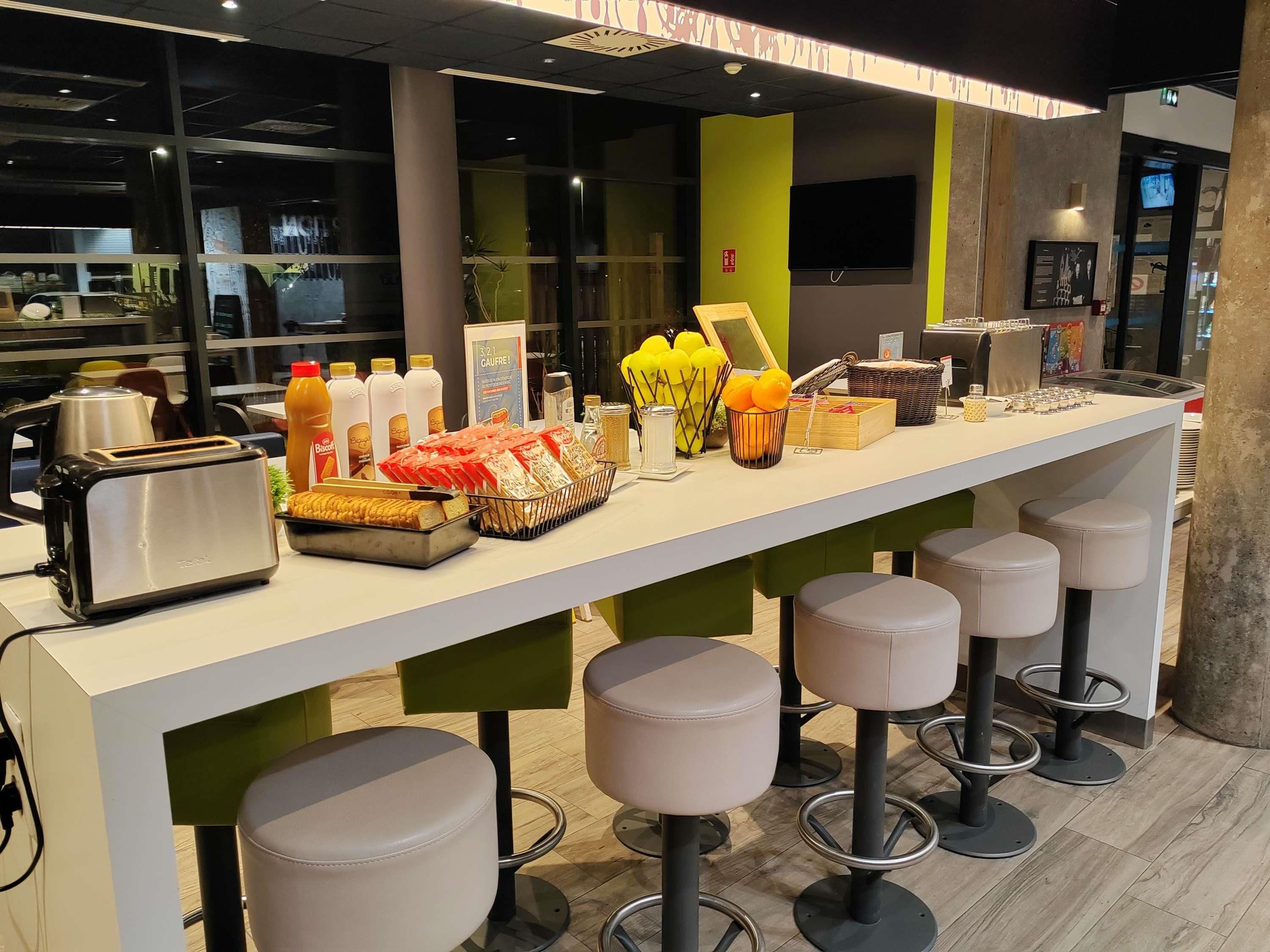 Zona de bar con taburetes, un tostador y diversos alimentos sobre la encimera.