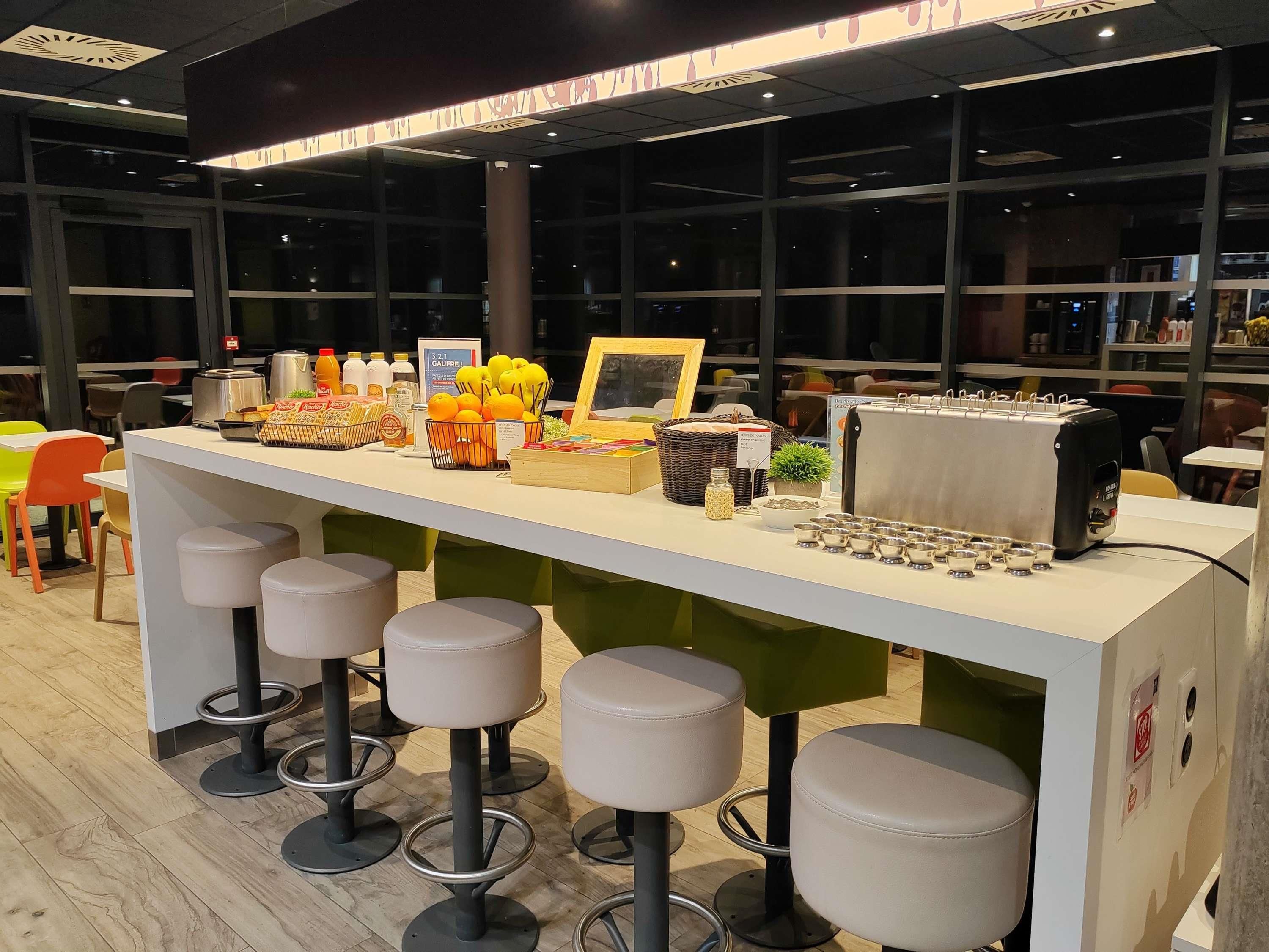 Un espace bar avec des tabourets, une machine à café et divers produits alimentaires.