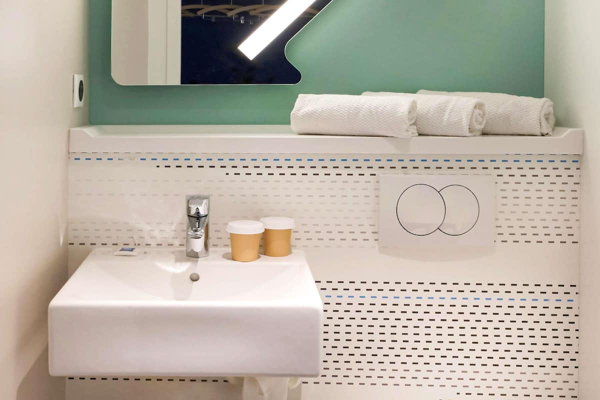 A bathroom with a white sink, a mirror, and a towel rack.