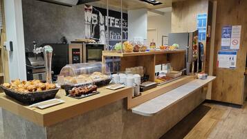 A buffet counter with various food items, a coffee machine, and a seating area.