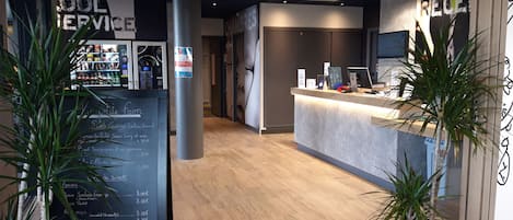Zona de recepción con mostrador, máquina expendedora y menú en una pizarra que enumera los alimentos.