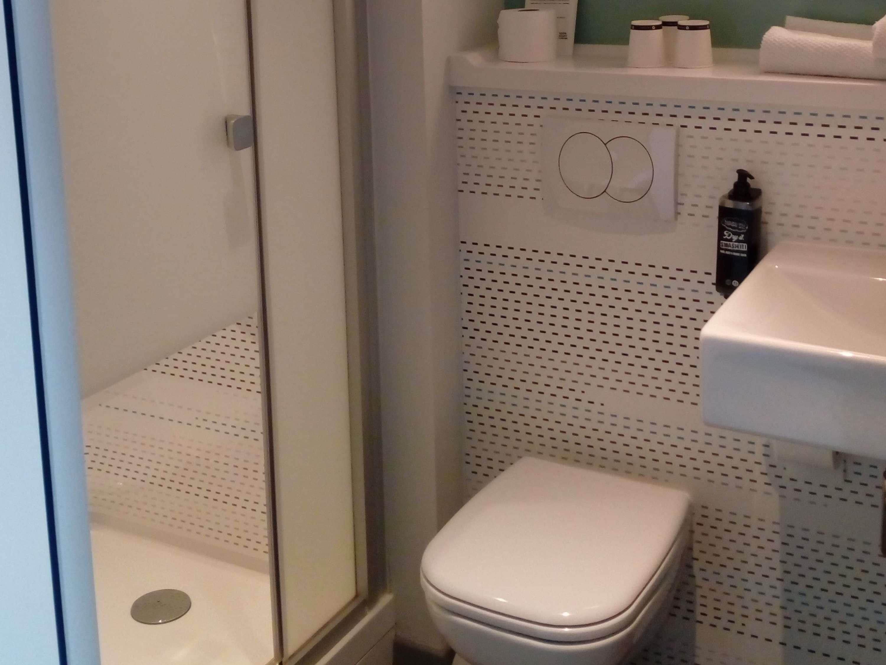 A bathroom with a toilet, a sink, and a shower area.