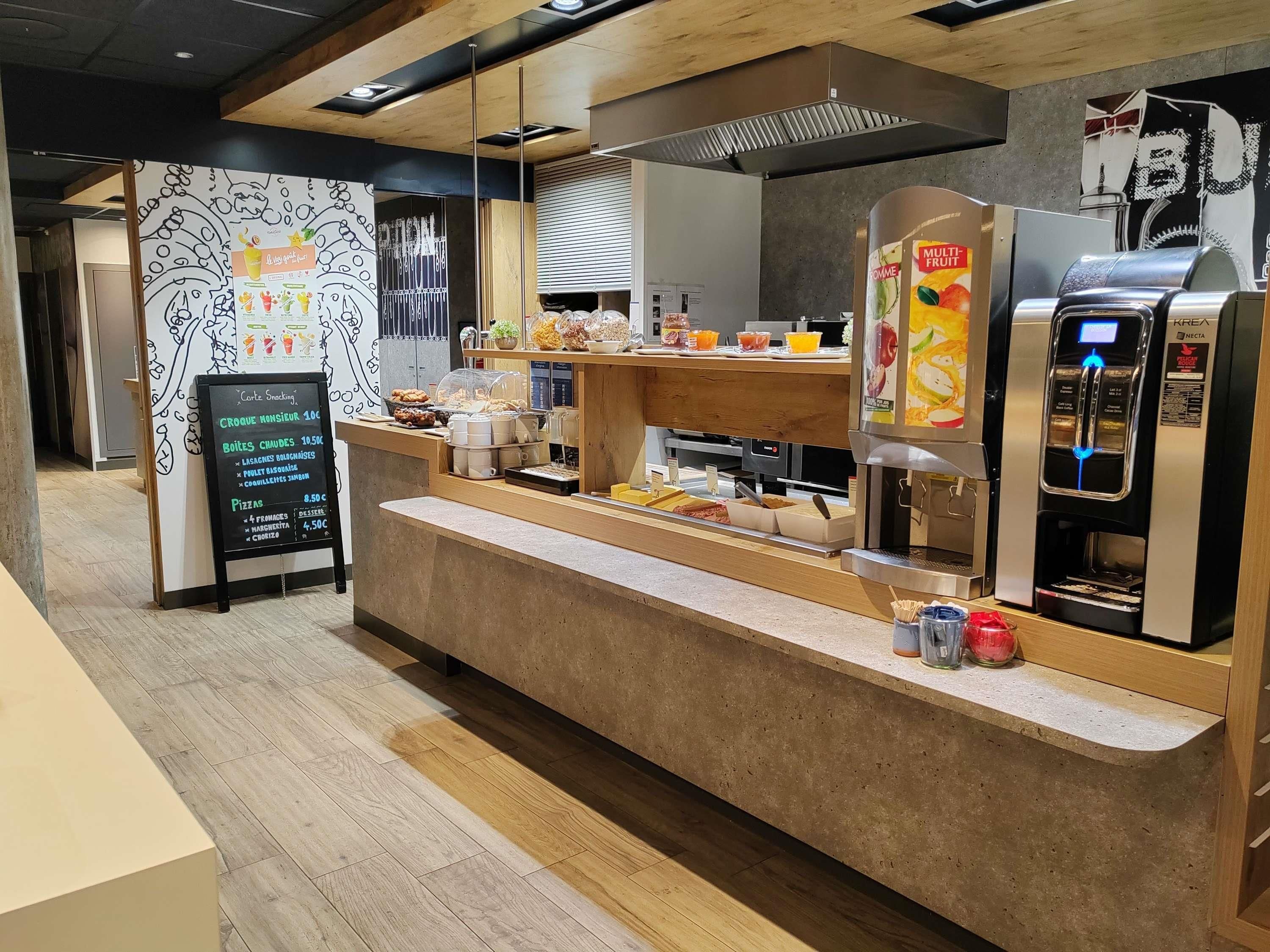 A cafe with a wooden counter, a menu board, and a beverage dispenser.