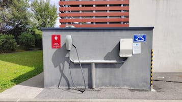 Una estación de carga Tesla con un letrero rojo, un cable de carga y un letrero azul que indica que es para vehículos eléctricos.