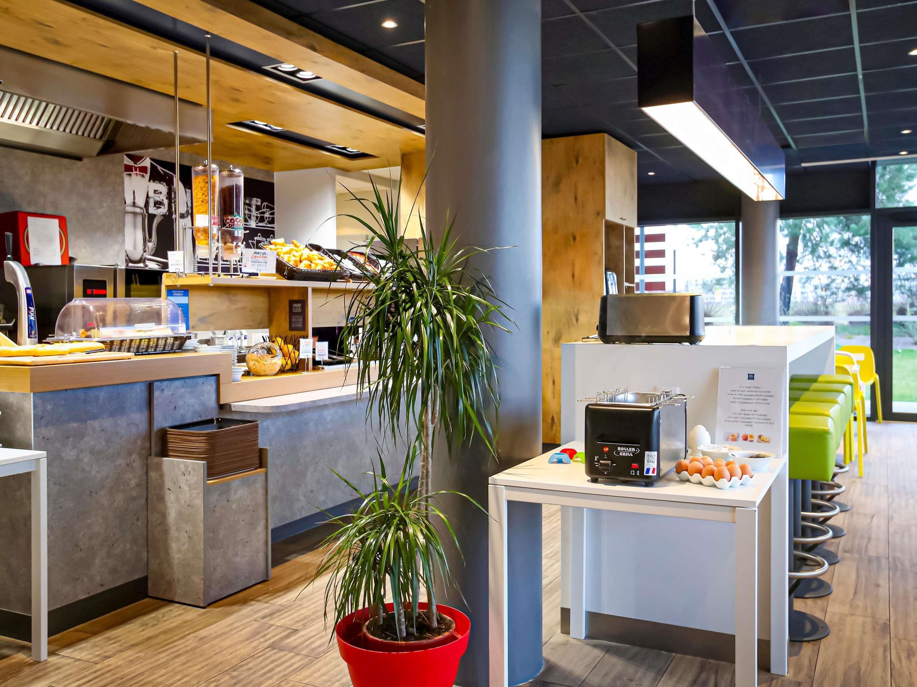 Un área de cocina moderna con una cafetera, una planta y una encimera con alimentos.