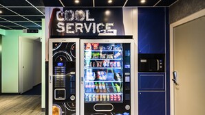 A vending machine with a variety of snacks and drinks, located in a room with a 'Cool Service' sign above it. - Ibis Budget Saint Genis Pouilly Geneva (Saint-Genis-Pouilly)