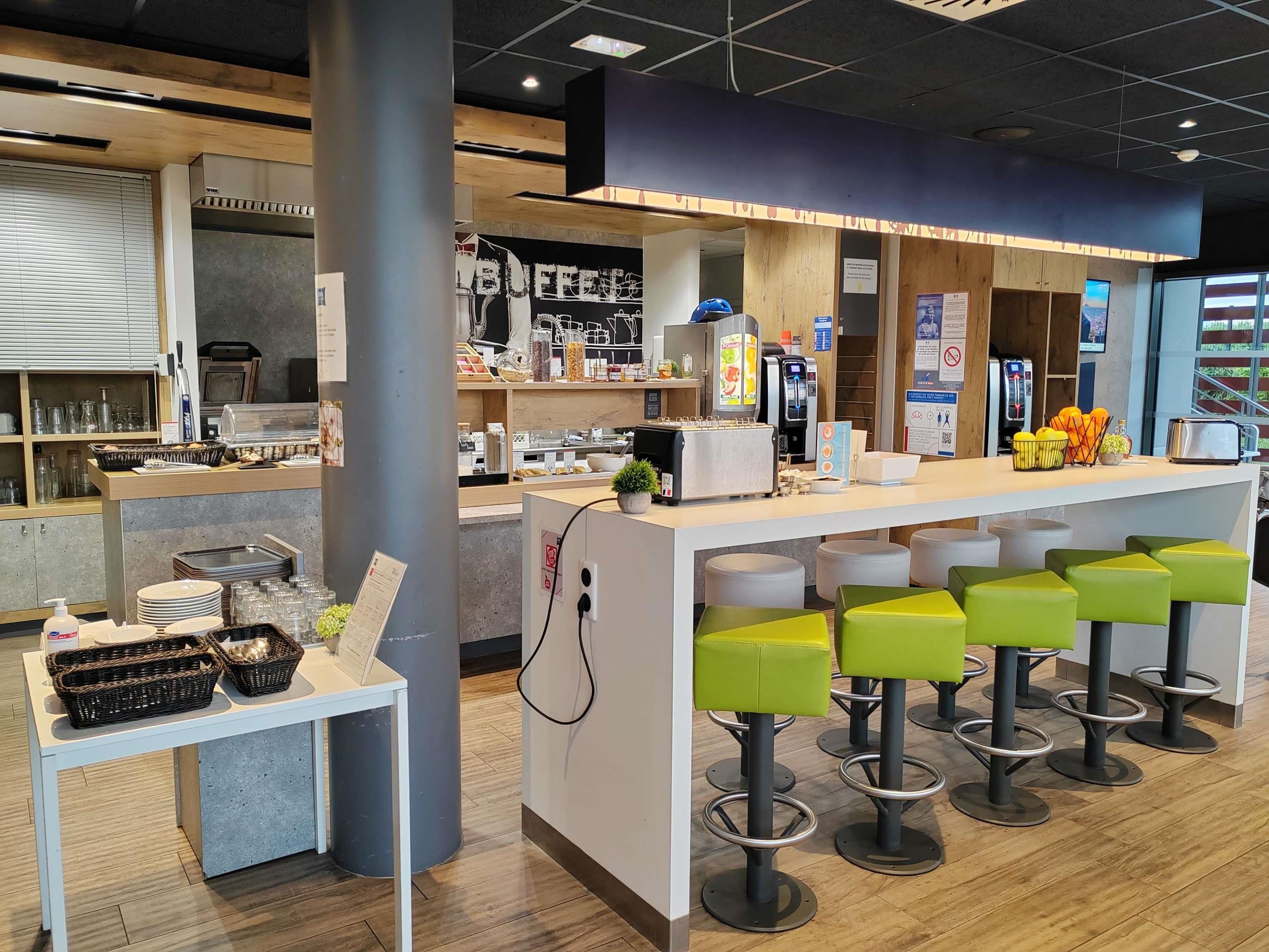 A modern cafe with a counter, bar stools, and various food items.