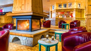 A cozy indoor seating area with leather chairs, a stone fireplace, and a bar area with wooden cabinets. - Azureva Areches Beaufort (Beaufort)