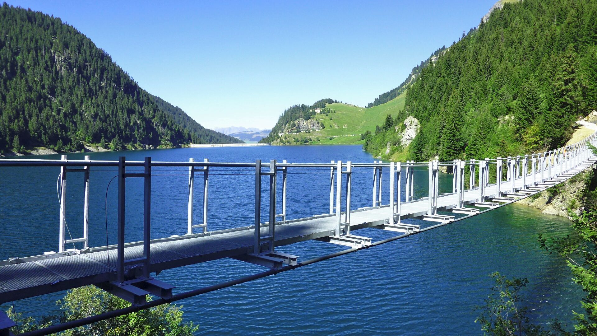 A long bridge over a lake with forested hills on either side.