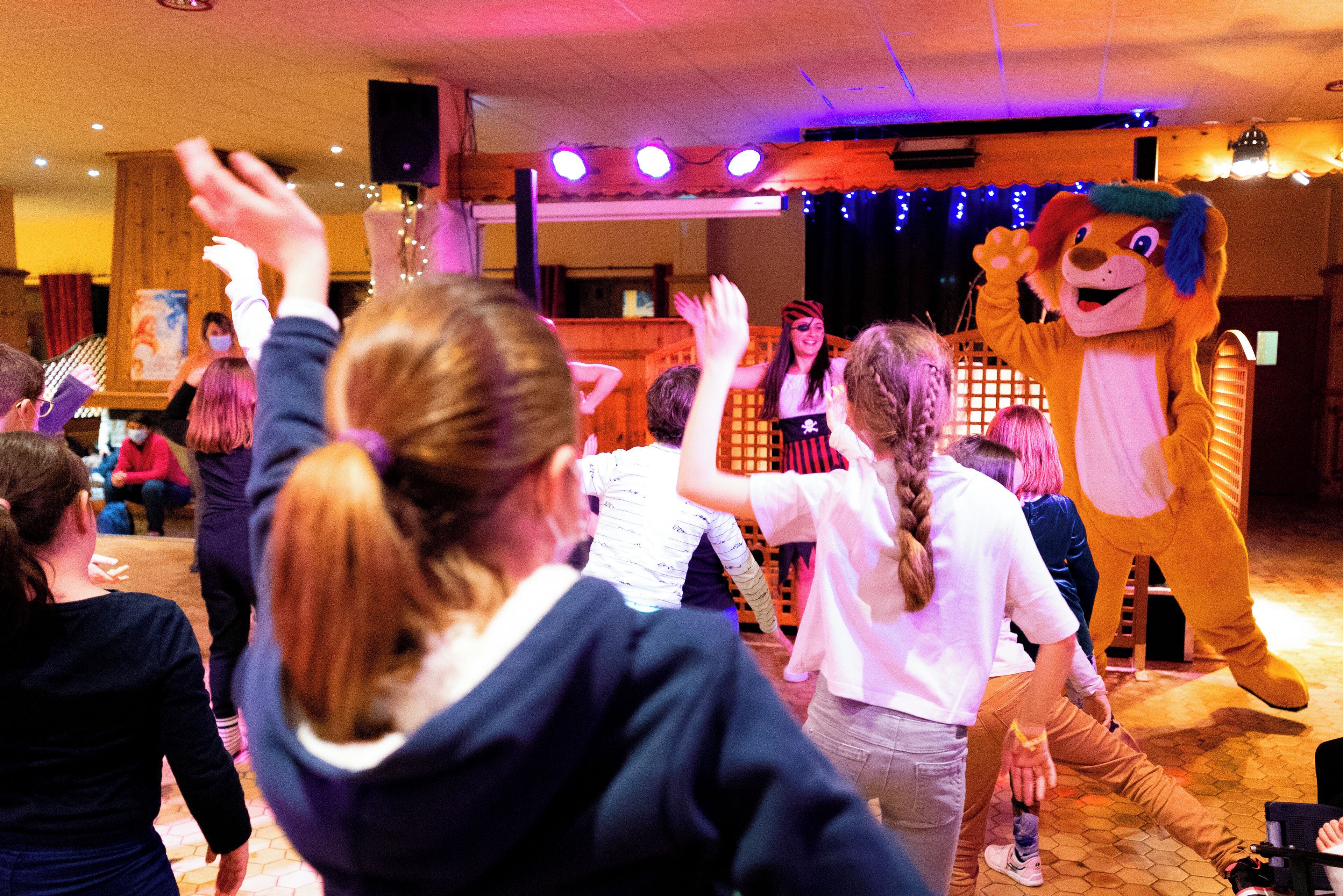 A group of people dancing in a room with wooden walls and a tiled floor.