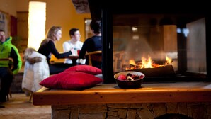 A cozy room with a fireplace, a wooden bench, and a bowl of fruit. - Azureva Areches Beaufort (Beaufort)