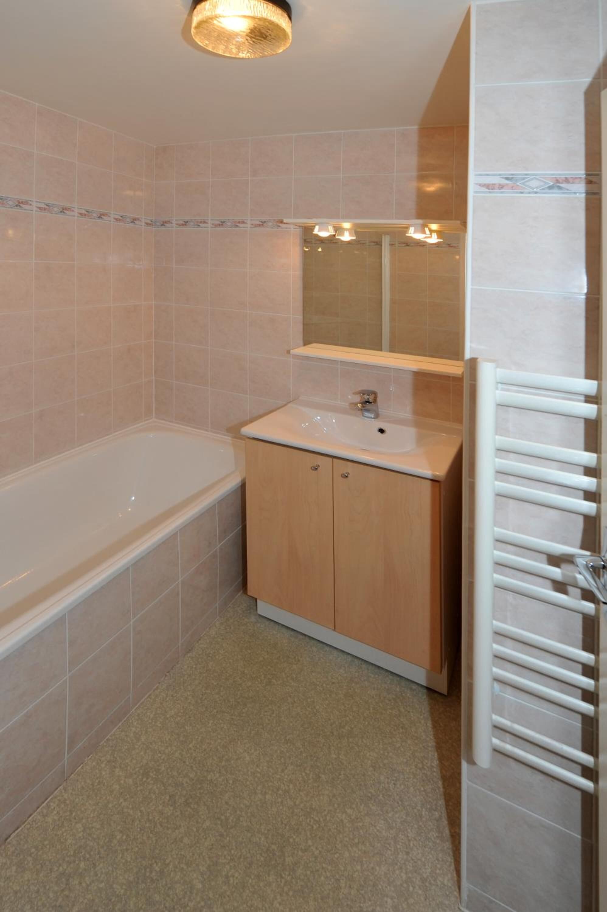 Een badkamer met een bad, een wastafel en een handdoekhouder.
