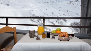 Una mesa de desayuno con vistas a montañas nevadas.