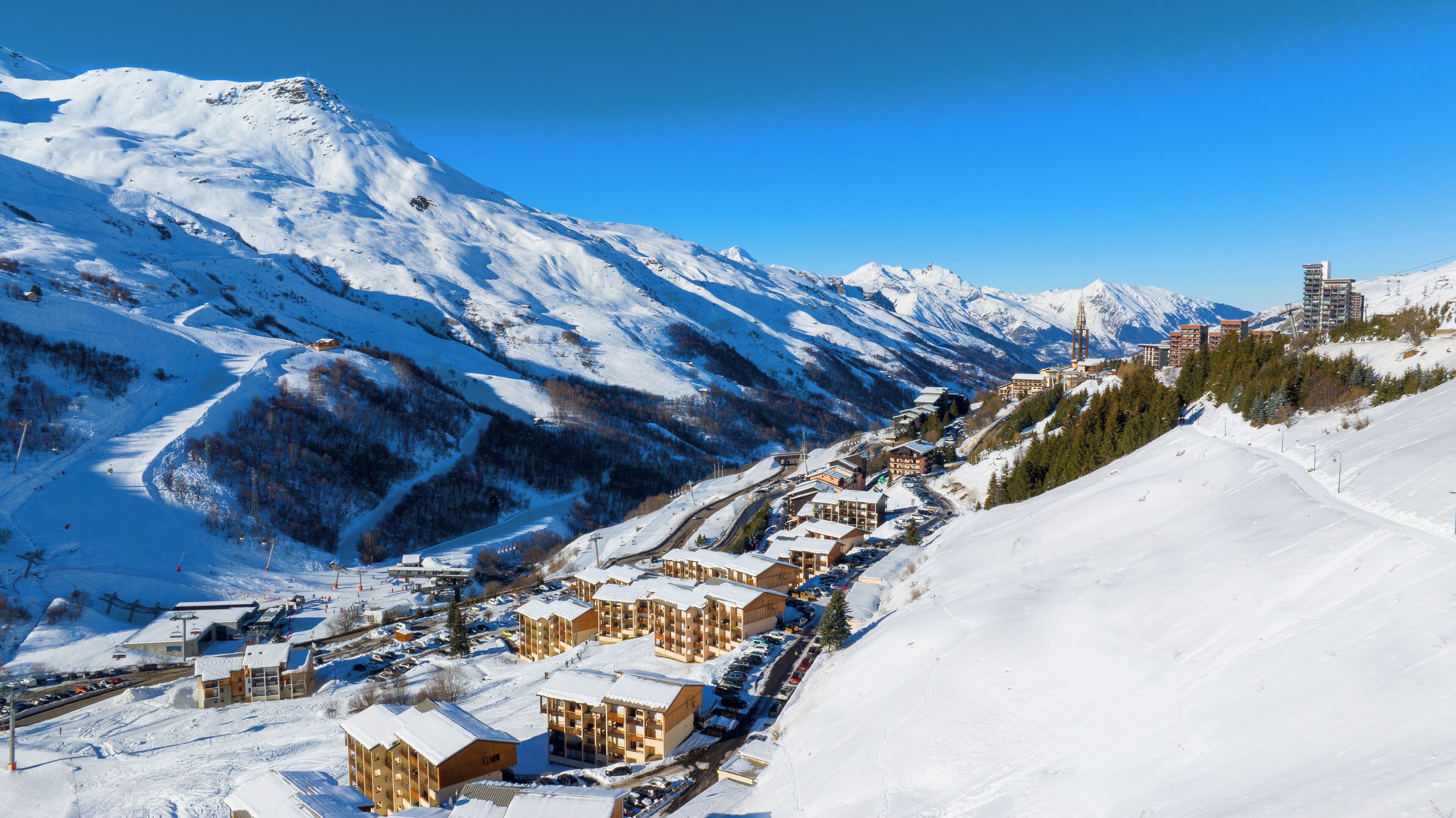 Une ville de montagne enneigée, avec des bâtiments qui bordent une route sinueuse.