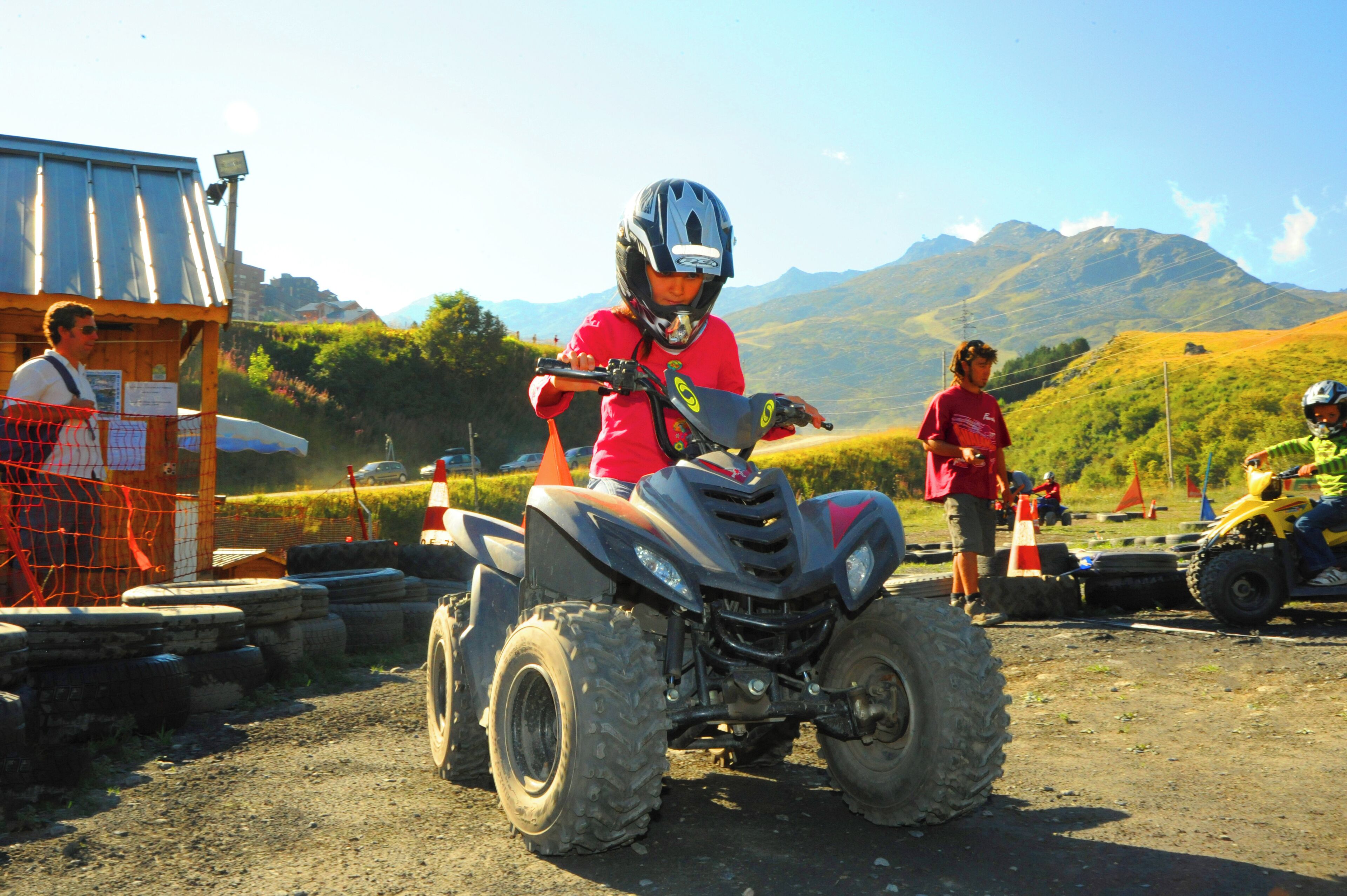 A person riding an ATV on a dirt path with mountains in the background.