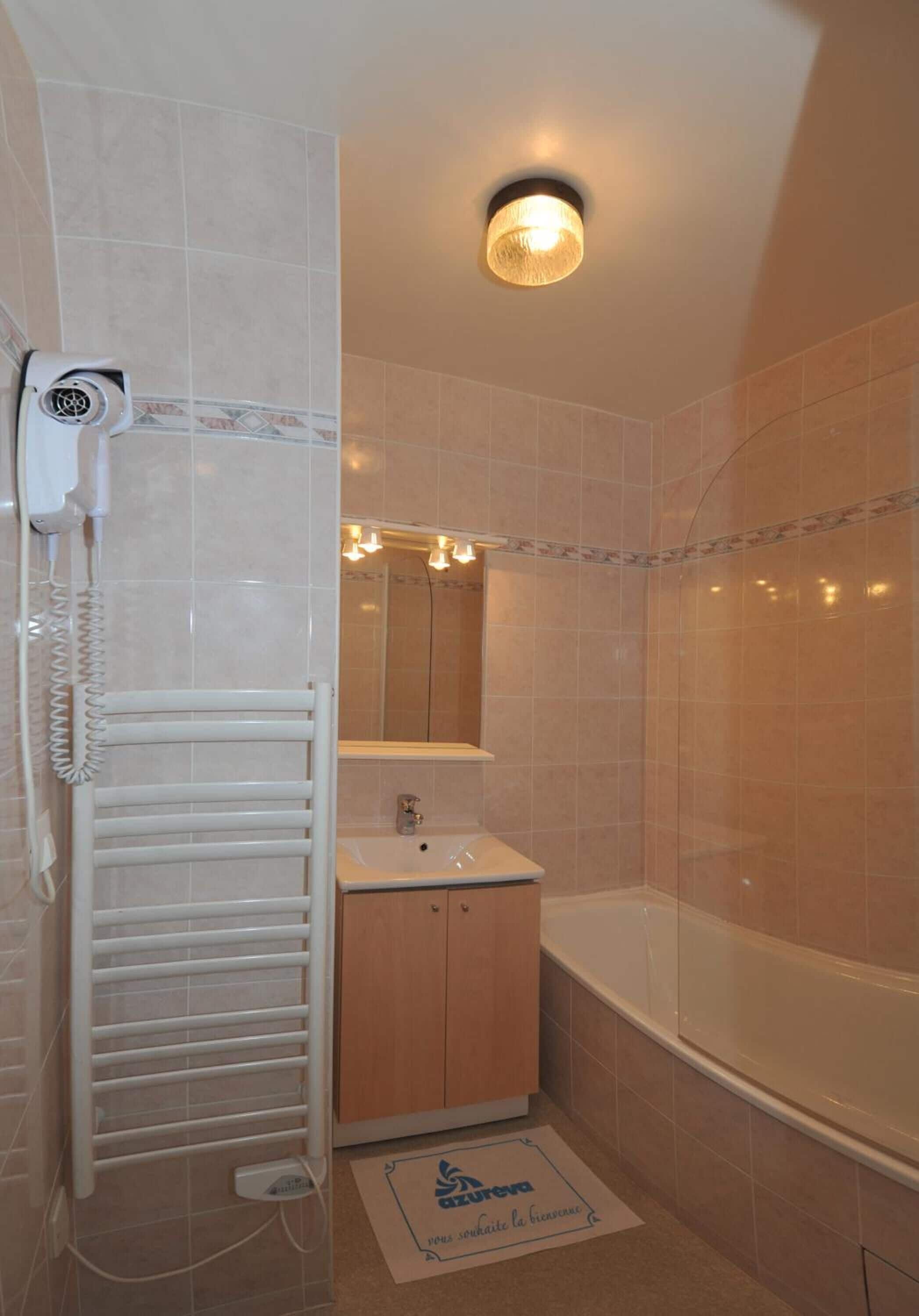 Un baño con toallero, lavabo, espejo y ducha.