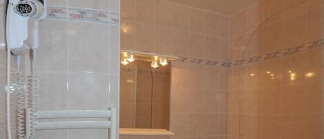 Un baño con toallero, lavabo, espejo y ducha.