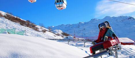 A chairlift at a ski resort with snow-covered slopes and mountains in the background.