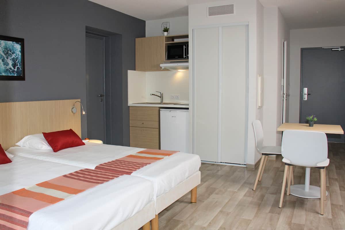 Une chambre d’hôtel équipée d’un lit, d’un bureau, d’une chaise, d’un four à micro-ondes et d’une petite kitchenette.