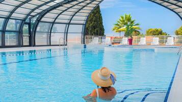 Una piscina cubierta, sombrillas, tumbonas