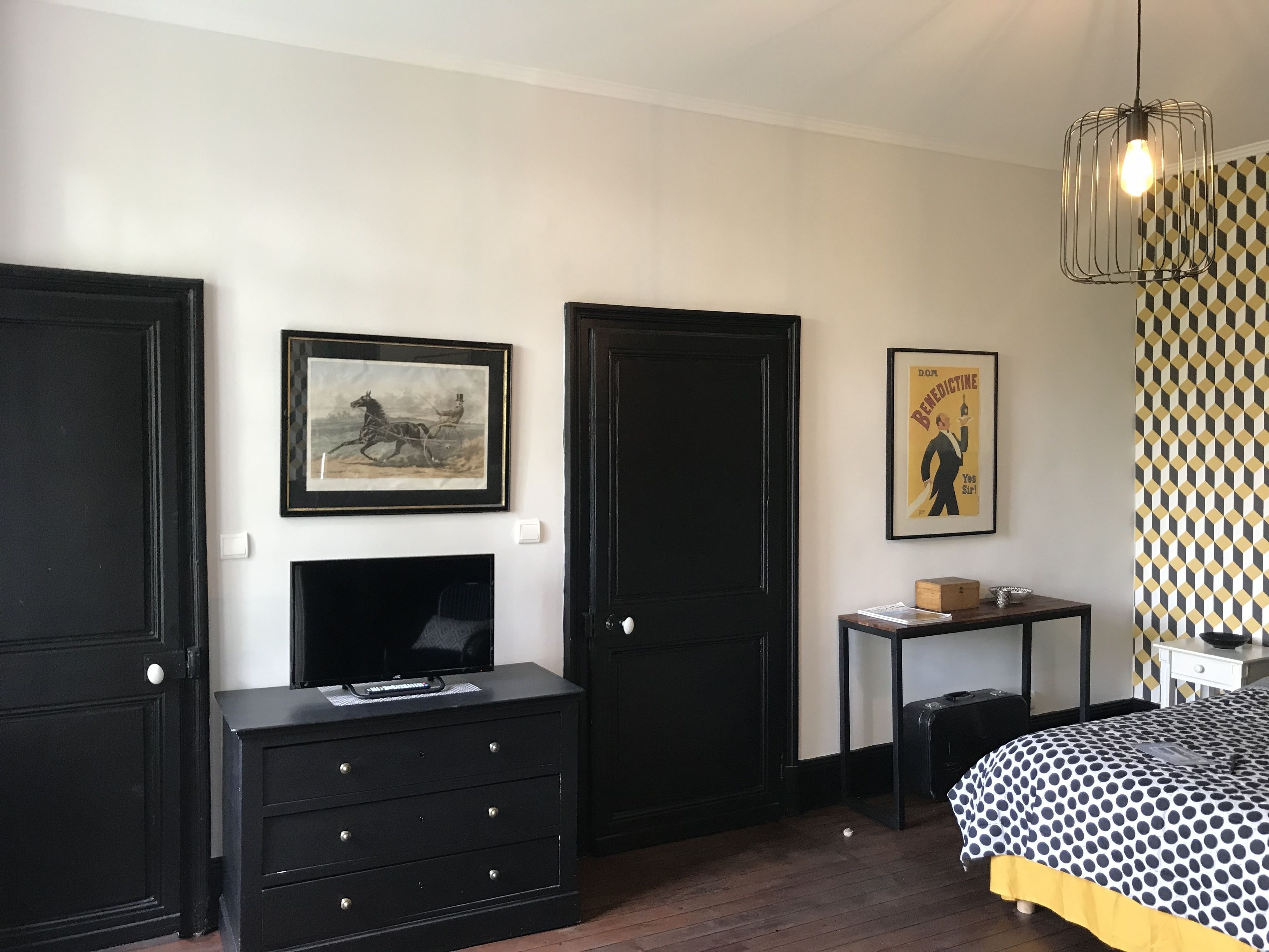 A bedroom with a bed, a dresser, a desk, and two doors.