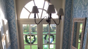 A hallway with a white door, a black mat, a radiator, and a patterned floor. - Le Clos des Hautes Loges (Les Loges)