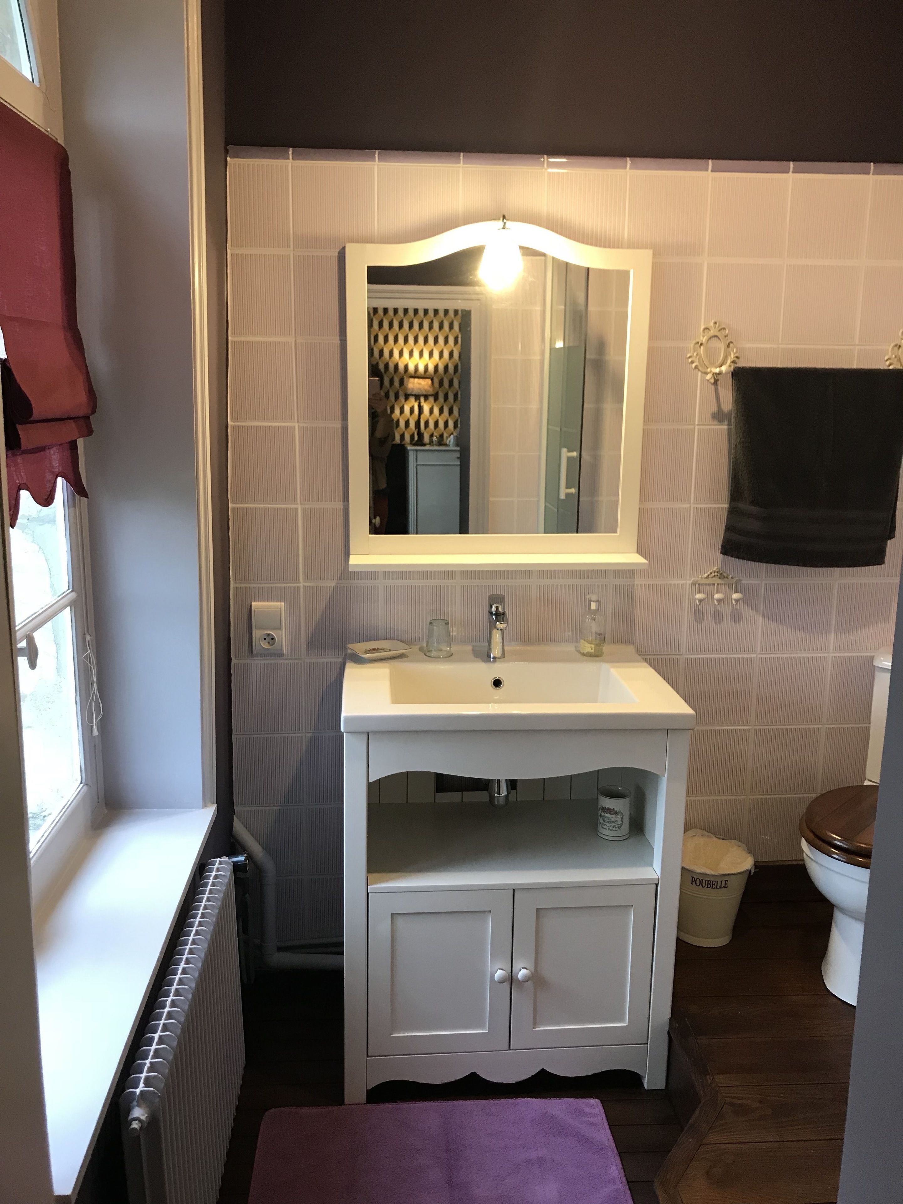 A bathroom with a white sink, mirror, and cabinet, a towel rack, and a toilet.