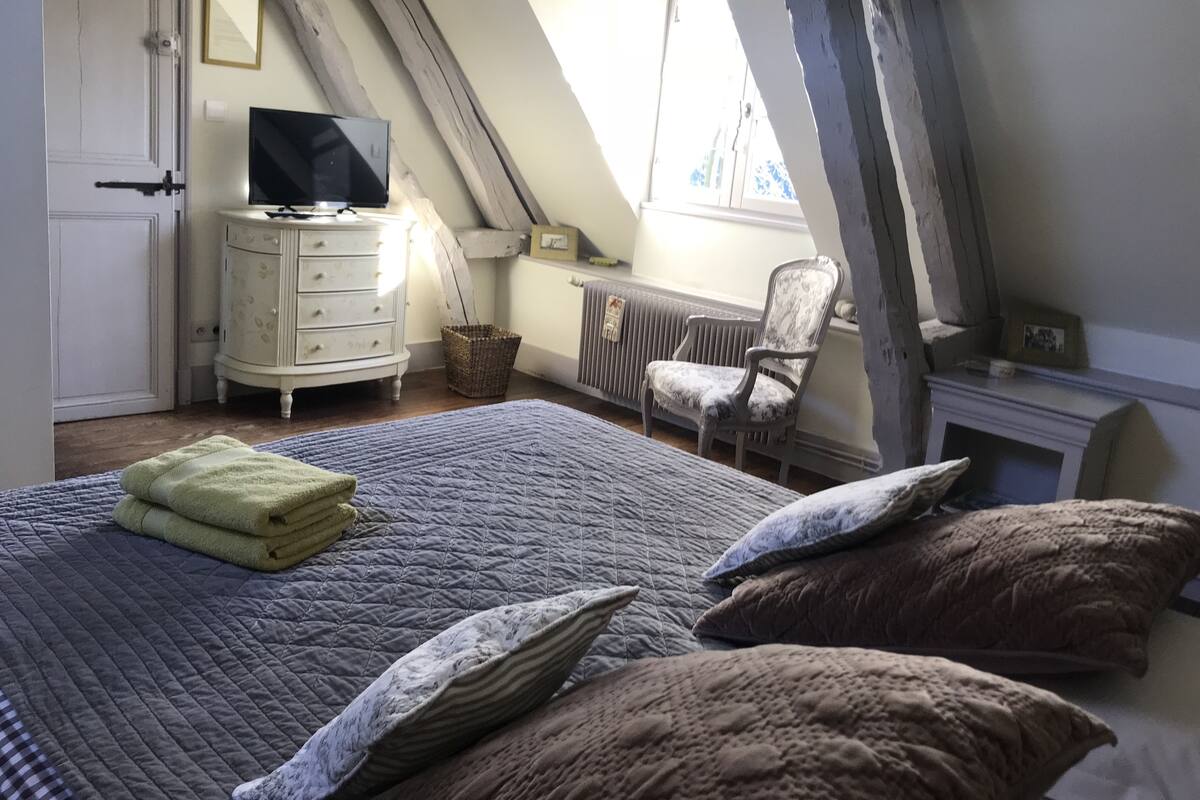Ein Schlafzimmer mit einem großen Bett, einem Schminktisch, einem Sessel, einem Fernseher und einem Fenster mit Aussicht.