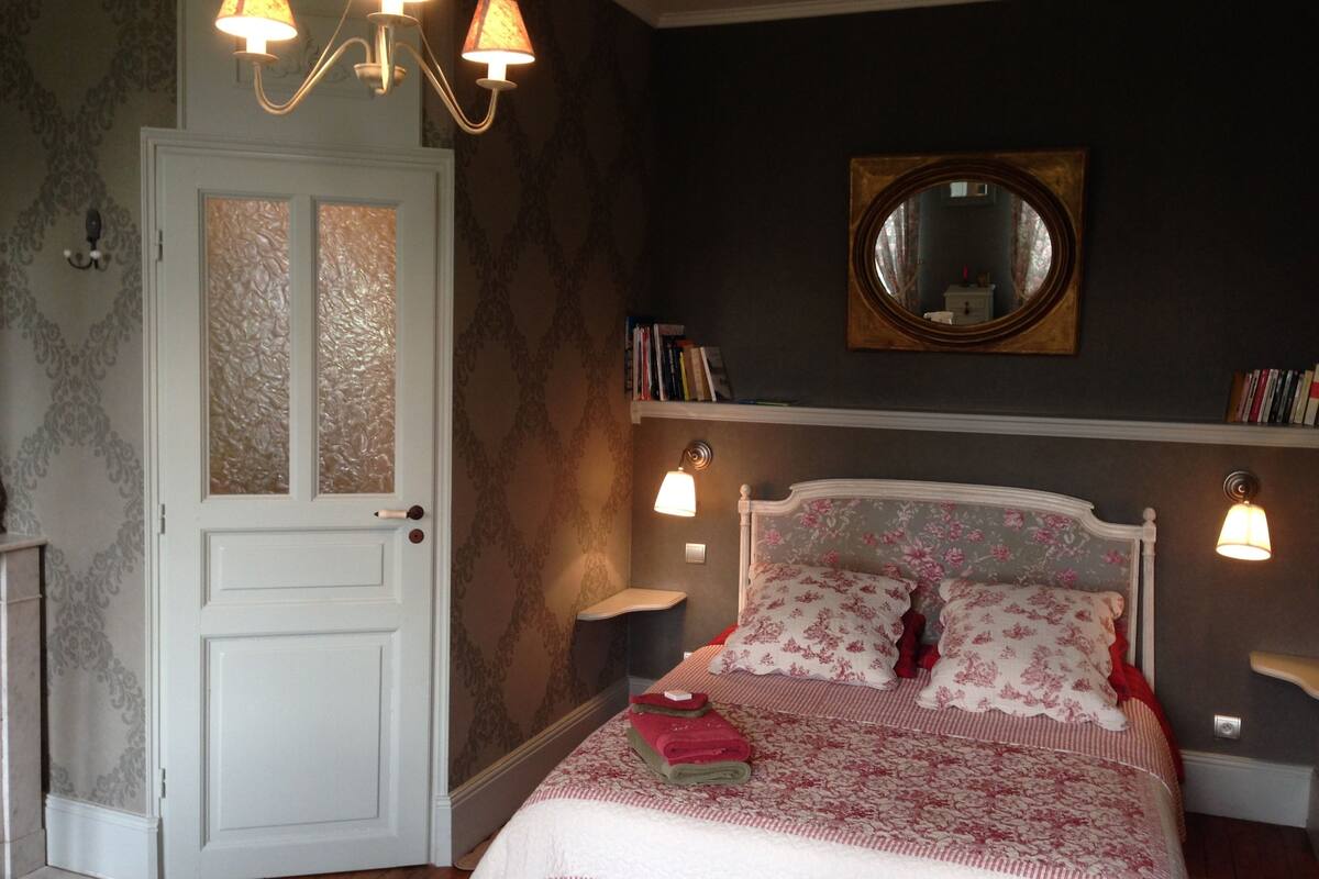 Ein Schlafzimmer mit Bett, Tür, Spiegel und Wandleuchten.