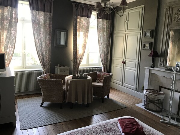 A room with a bed, a table with chairs, a radiator, a fireplace, and curtains. - Le Clos des Hautes Loges (Les Loges)