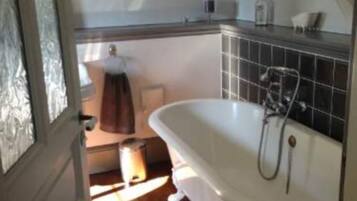 A bathroom with a freestanding bathtub, a towel rack, and a mirror.