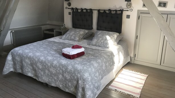 A bedroom with a bed, a radiator, a nightstand, and a small window. - Le Clos des Hautes Loges (Les Loges)