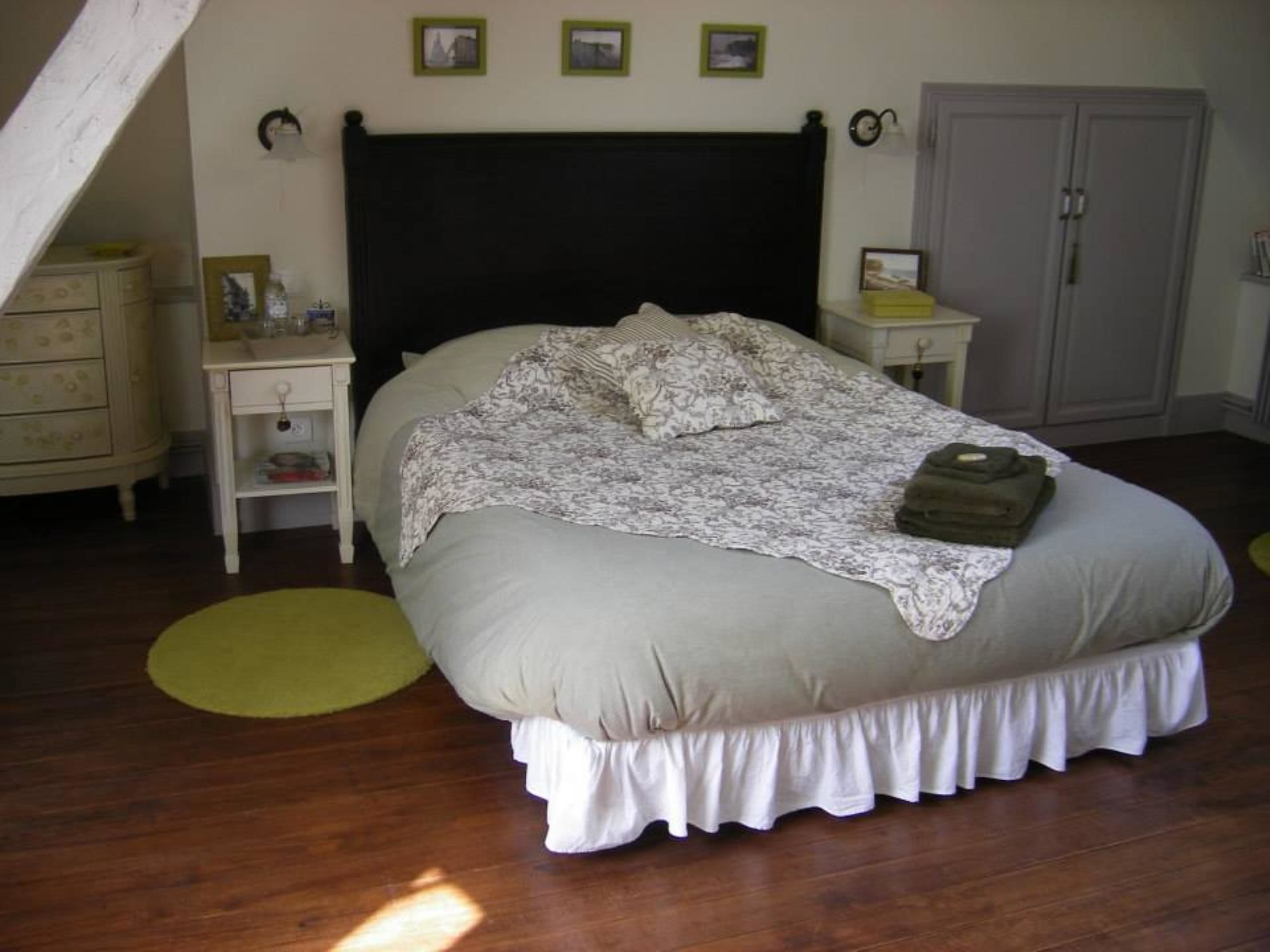 A bedroom with a bed, a nightstand, a dresser, and a wardrobe.
