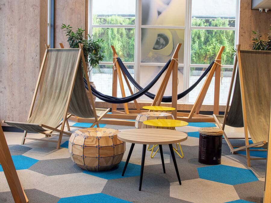 A room with a hammock, easels, a round table, and a wooden stool.