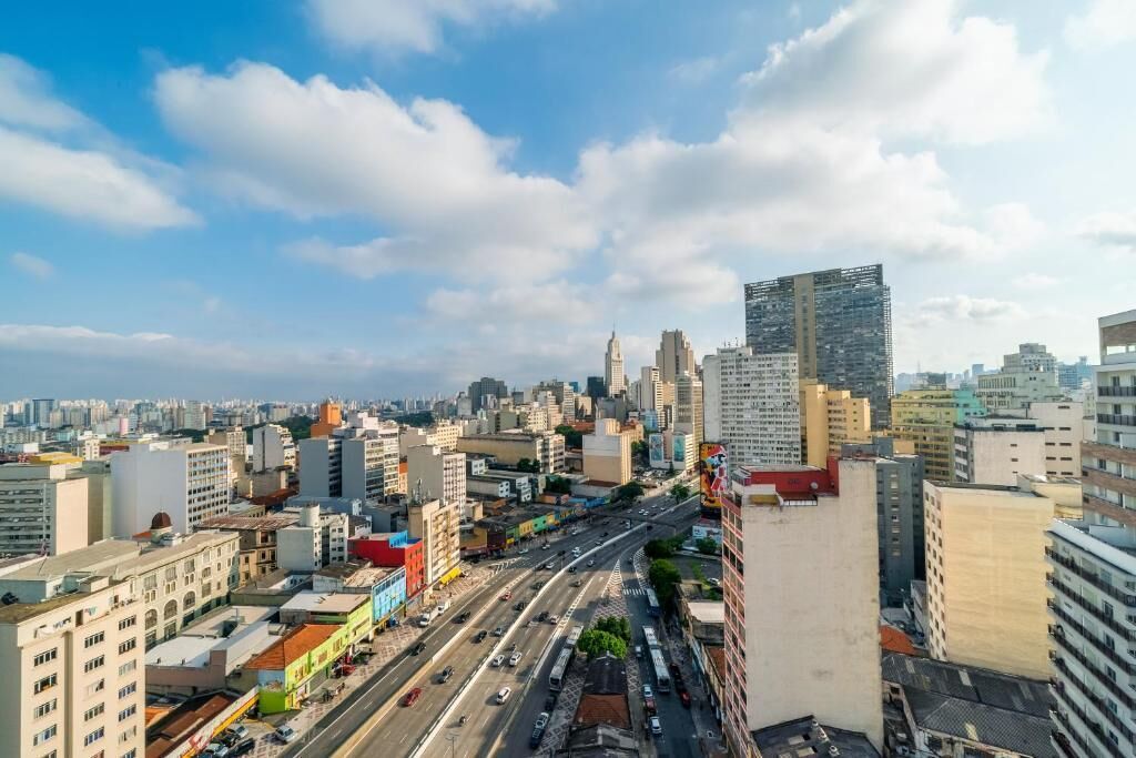 Paesaggio urbano con un mix di edifici moderni e antichi, strade trafficate e cielo sereno.
